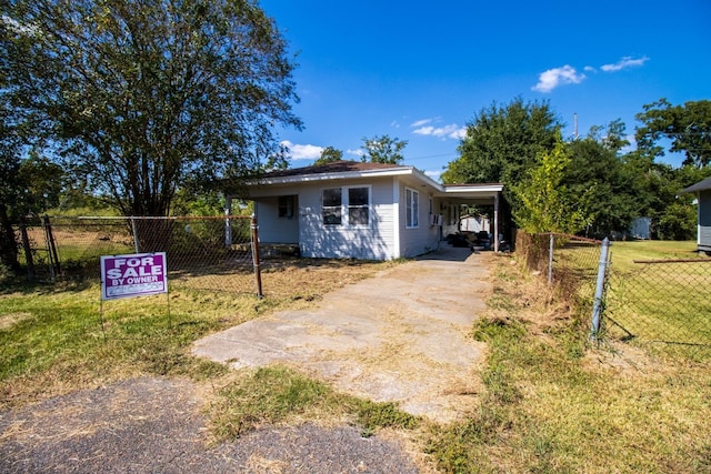 view of front of house with driveway, fence, a carport, and a front yard