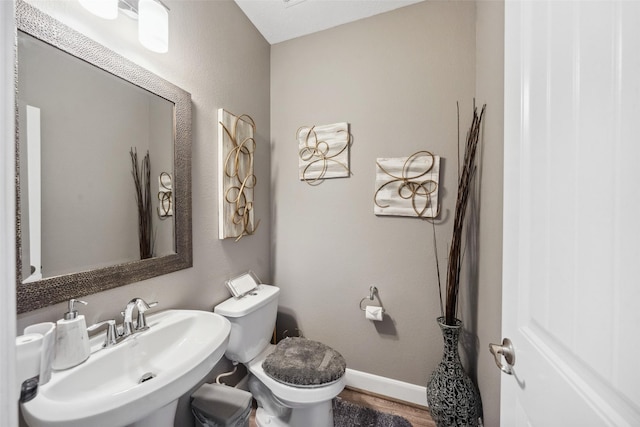 bathroom with wood finished floors, a sink, toilet, and baseboards