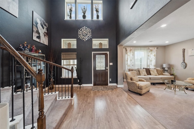 foyer with stairs, a high ceiling, wood finished floors, and baseboards