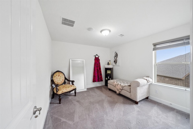 living area featuring baseboards, visible vents, and light colored carpet