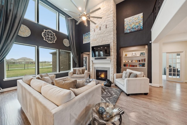 living room with light wood-style flooring, baseboards, and a stone fireplace