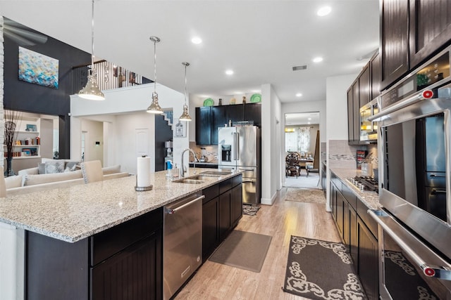 kitchen with visible vents, an island with sink, stainless steel appliances, pendant lighting, and a sink