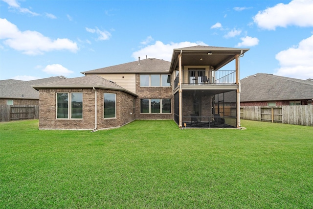 back of house with a fenced backyard, a balcony, brick siding, a sunroom, and a lawn