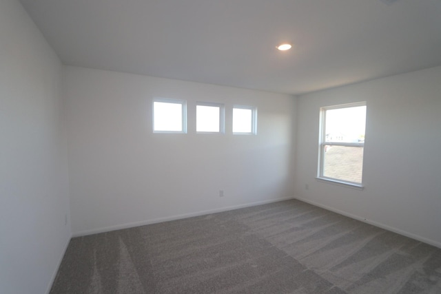 spare room with recessed lighting, dark carpet, and baseboards