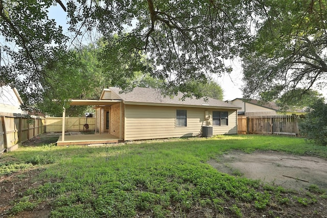 rear view of house with a fenced backyard, a lawn, central AC unit, and a patio