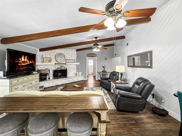 living room featuring a textured ceiling, a stone fireplace, baseboards, dark wood-style floors, and beamed ceiling