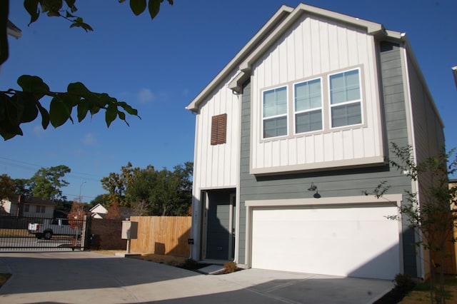 modern farmhouse featuring board and batten siding, concrete driveway, fence, and a garage