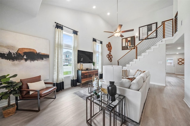 living area with baseboards, a ceiling fan, light wood-style flooring, stairs, and recessed lighting