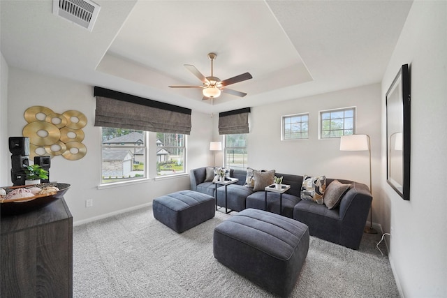 living area featuring baseboards, visible vents, ceiling fan, a tray ceiling, and carpet flooring