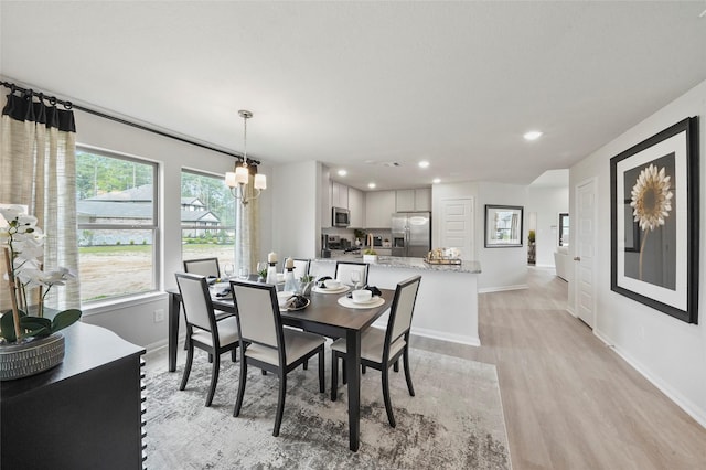 dining space featuring light wood-type flooring, an inviting chandelier, baseboards, and recessed lighting