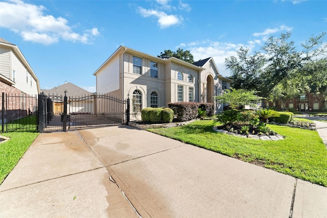 view of front facade with driveway, a fenced front yard, a gate, a front lawn, and brick siding