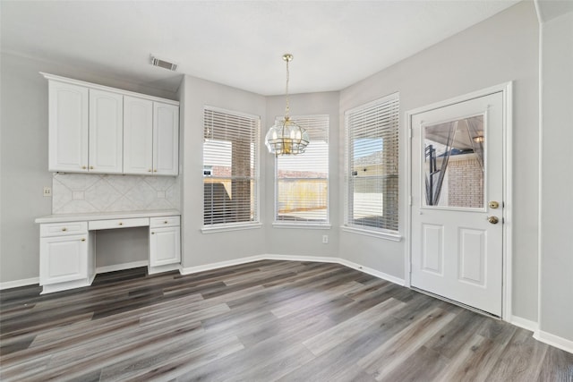 unfurnished dining area with baseboards, visible vents, and dark wood finished floors