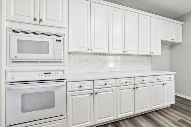 kitchen featuring white appliances, white cabinets, light countertops, backsplash, and dark wood-style floors