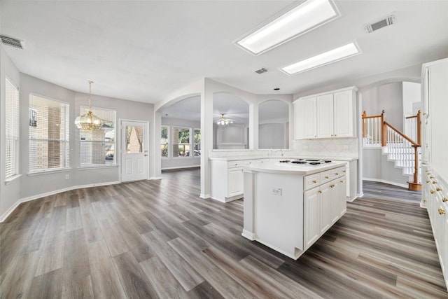 kitchen with arched walkways, white cabinets, light countertops, and visible vents