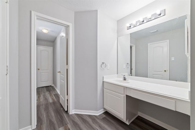 bathroom featuring baseboards, wood finished floors, and vanity