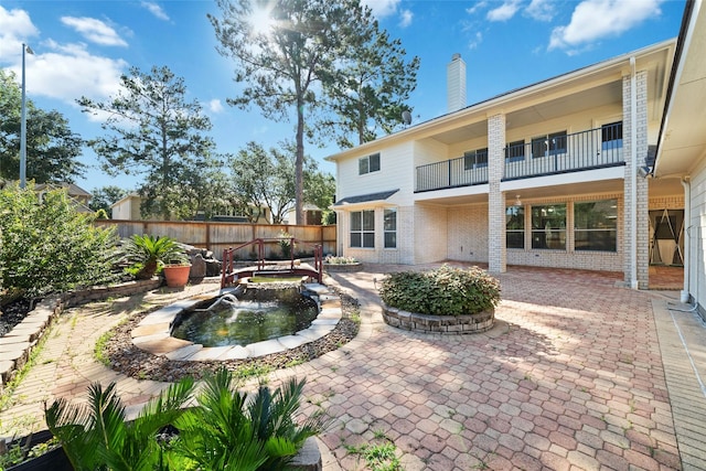 rear view of property featuring a fenced backyard, a chimney, a patio, and brick siding