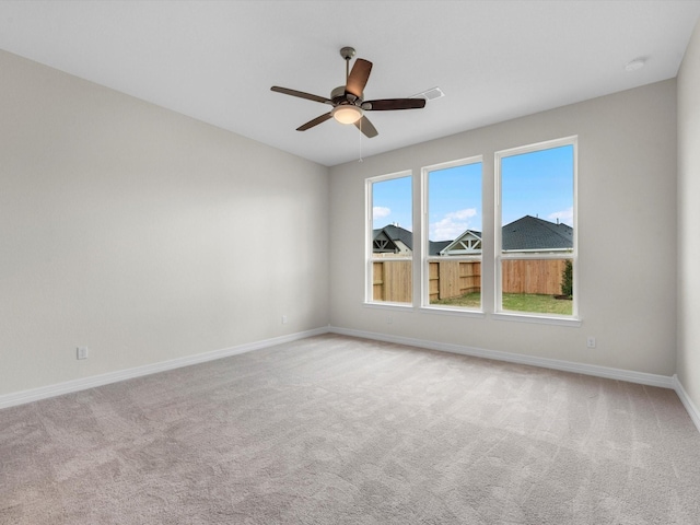 empty room featuring ceiling fan, baseboards, and light colored carpet