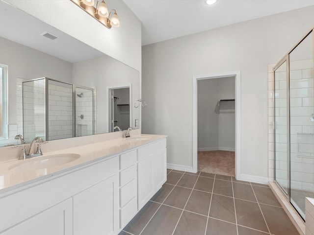 full bathroom with a shower stall, a walk in closet, a sink, and tile patterned floors