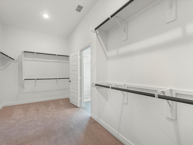 walk in closet with visible vents and light colored carpet