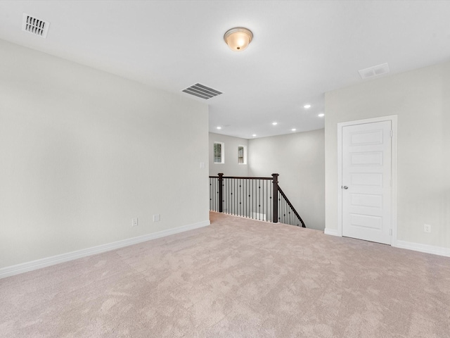 empty room with light colored carpet, recessed lighting, visible vents, and baseboards