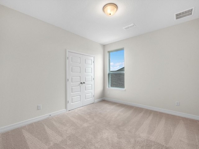 unfurnished room with light colored carpet, visible vents, and baseboards