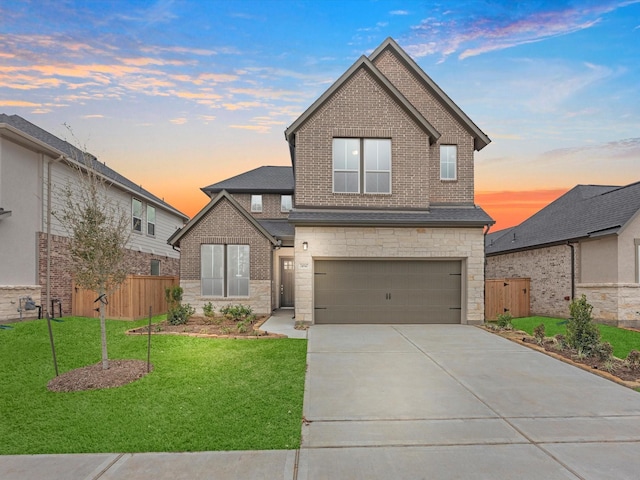 view of front of house featuring driveway, stone siding, an attached garage, fence, and a front lawn