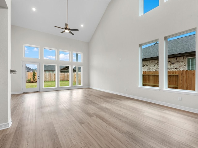 unfurnished living room featuring baseboards, a high ceiling, recessed lighting, and light wood-style floors