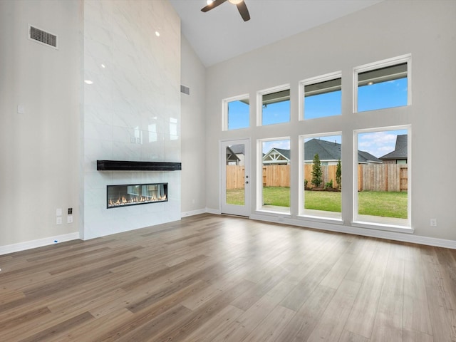 unfurnished living room featuring high vaulted ceiling, a tiled fireplace, and wood finished floors