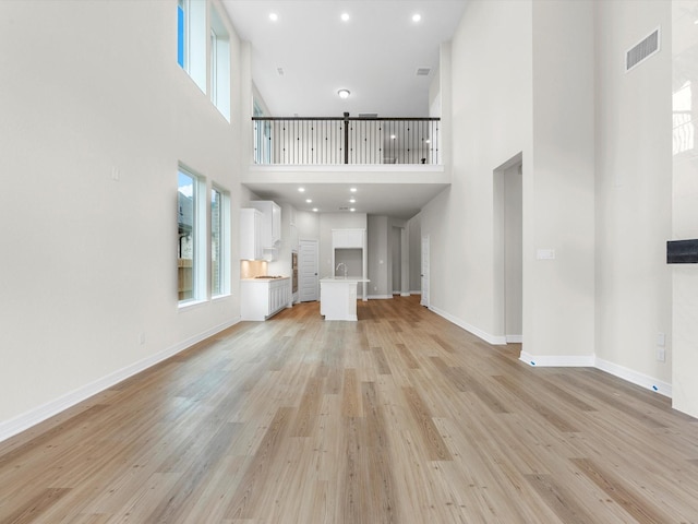 unfurnished living room with a healthy amount of sunlight, visible vents, and light wood finished floors