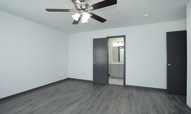 unfurnished bedroom featuring a ceiling fan, connected bathroom, baseboards, and wood finished floors