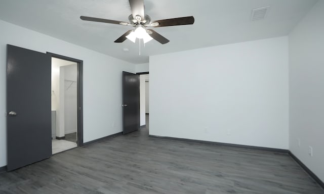 spare room featuring a ceiling fan, baseboards, visible vents, and dark wood-style flooring