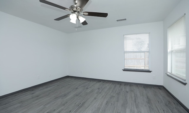 empty room with dark wood-style floors, baseboards, and visible vents