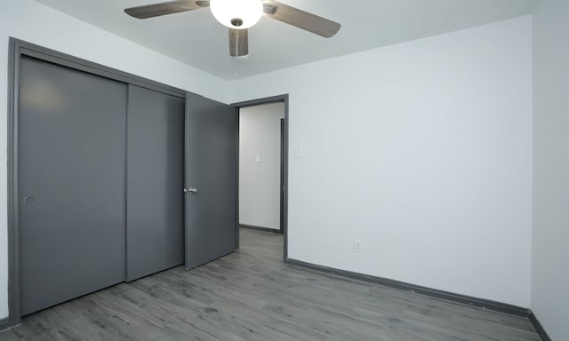 unfurnished bedroom with ceiling fan, a closet, baseboards, and light wood-style floors