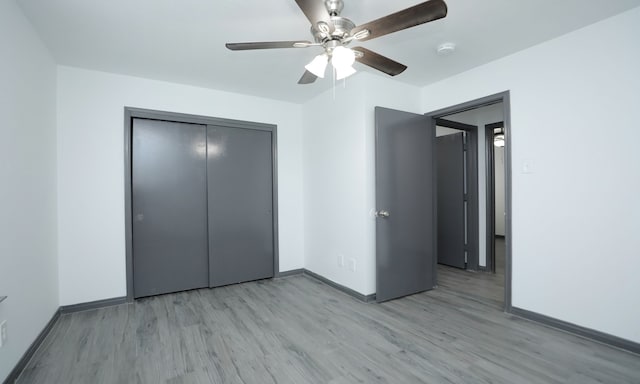 unfurnished bedroom featuring light wood-type flooring, a closet, ceiling fan, and baseboards