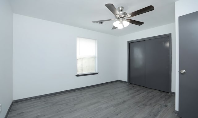 unfurnished bedroom featuring visible vents, a ceiling fan, baseboards, a closet, and dark wood-style floors