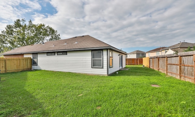 back of property with a fenced backyard and a lawn