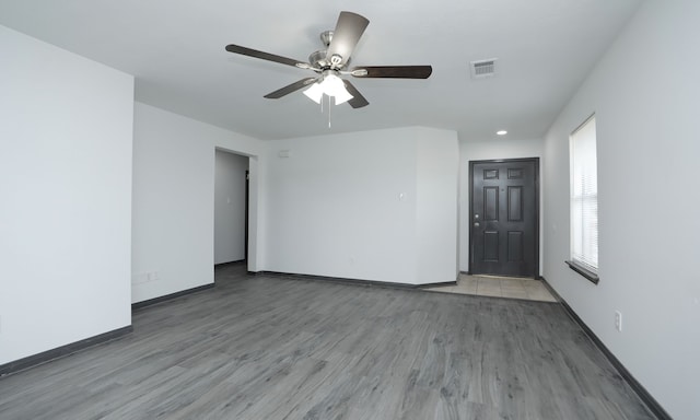 unfurnished room featuring ceiling fan, wood finished floors, visible vents, and baseboards