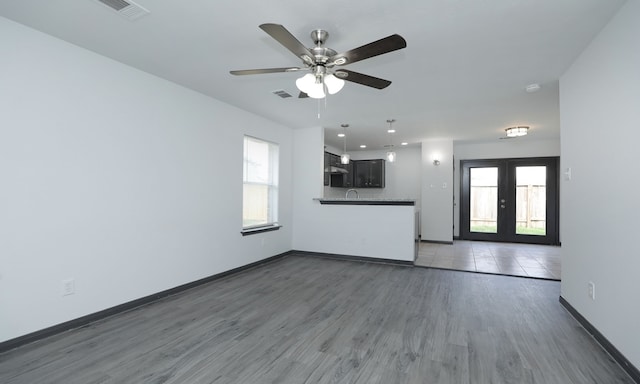 unfurnished living room with french doors, dark wood finished floors, visible vents, and baseboards