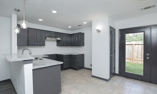 kitchen with visible vents, decorative backsplash, a peninsula, under cabinet range hood, and pendant lighting