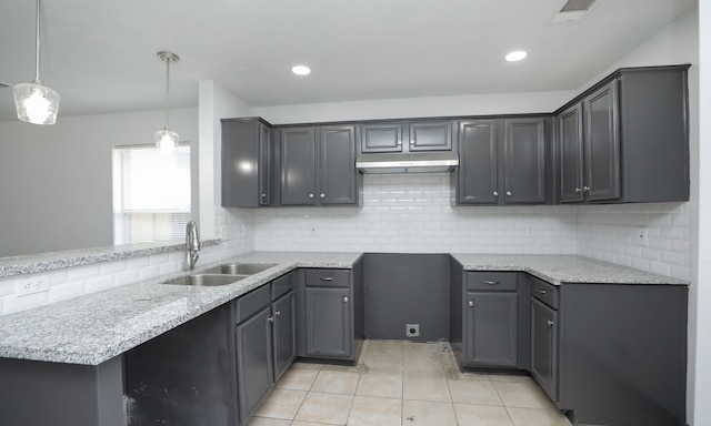 kitchen featuring visible vents, gray cabinets, under cabinet range hood, pendant lighting, and a sink