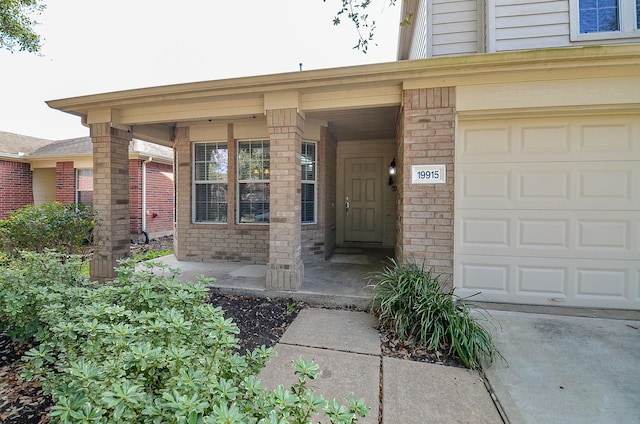 entrance to property featuring a garage and brick siding