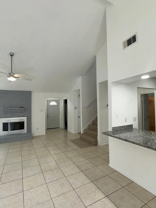 unfurnished living room with visible vents, ceiling fan, stairs, a fireplace, and light tile patterned flooring