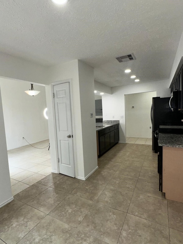 kitchen featuring dark countertops, visible vents, stainless steel microwave, and a textured ceiling