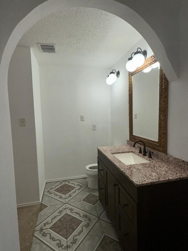 bathroom featuring visible vents, toilet, tile patterned floors, a textured ceiling, and vanity