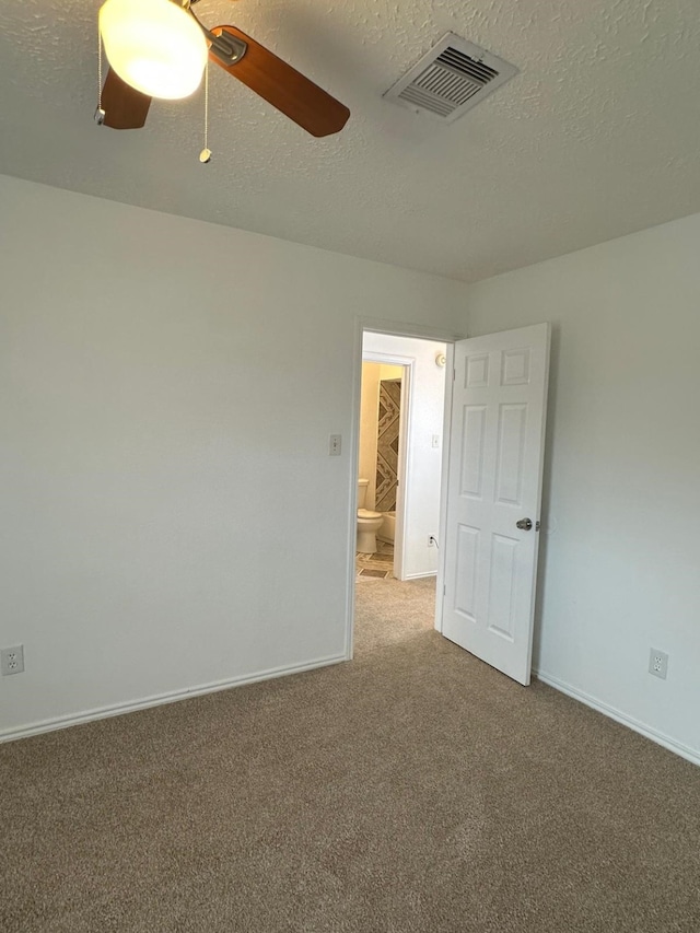 unfurnished room with carpet floors, visible vents, ceiling fan, a textured ceiling, and baseboards