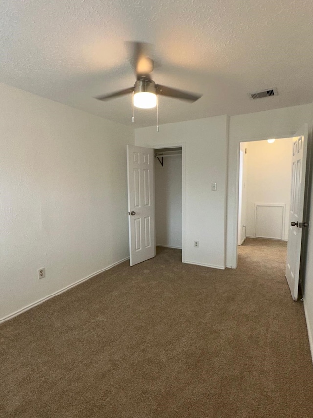 unfurnished bedroom featuring carpet floors, a ceiling fan, visible vents, and a textured ceiling