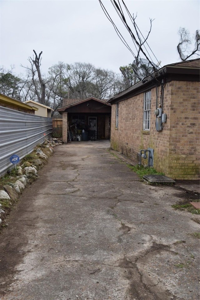 view of property exterior with driveway, fence, and brick siding