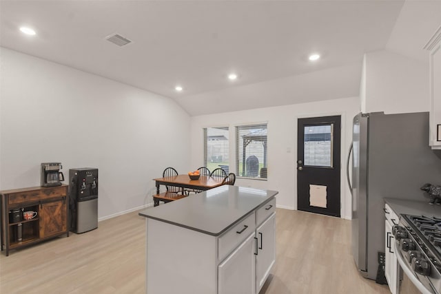 kitchen featuring visible vents, white cabinets, vaulted ceiling, a center island, and stainless steel range with gas stovetop