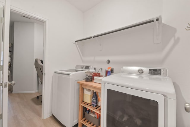 clothes washing area featuring laundry area, washing machine and clothes dryer, and light wood-style flooring