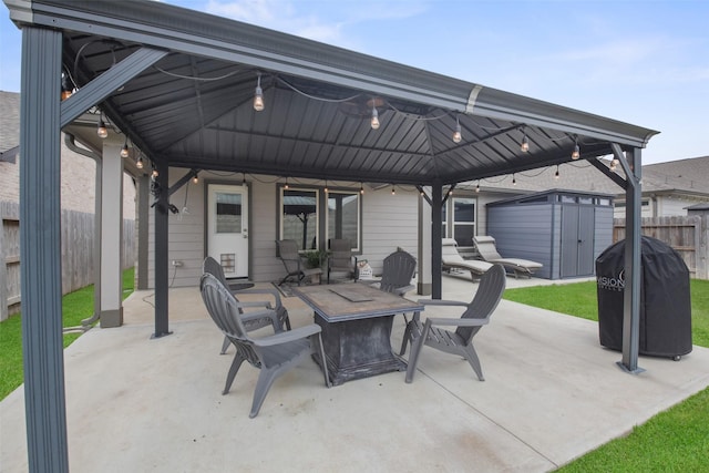 view of patio / terrace featuring an outdoor fire pit, a gazebo, fence, a storage unit, and an outdoor structure